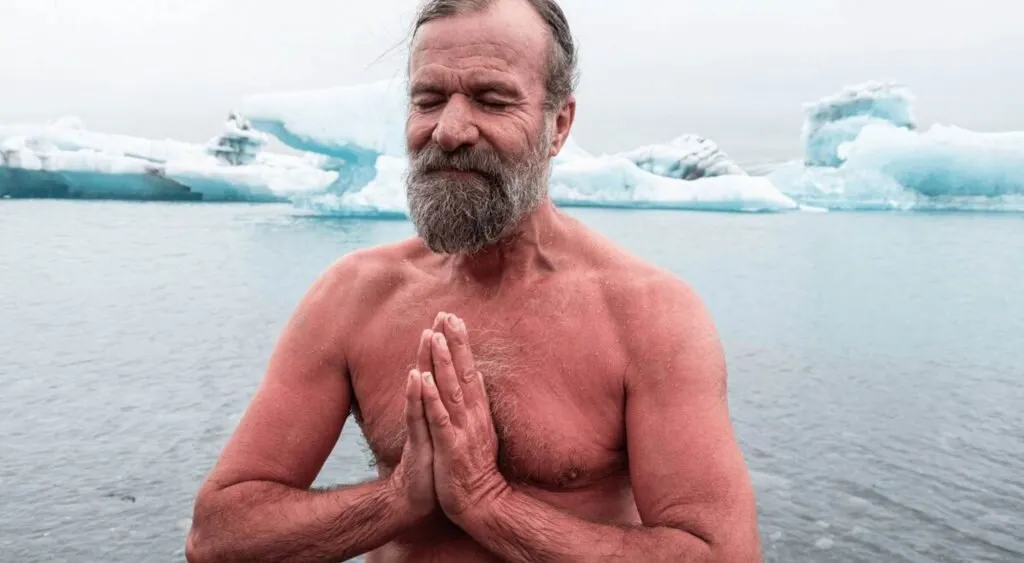 Wim Hof standing in icy water with his palms pressed together